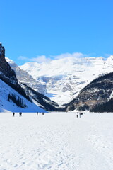 Lake Louise, Alberta, Canada - Apr 13, 2025: Tourists walking on the frozen Lake Louise. Beautiful...