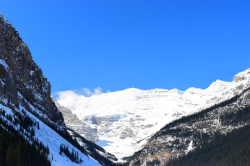 Fototapeta premium Lake Louise, Alberta, Canada - Apr 13, 2025: Tourists walking on the frozen Lake Louise. Beautiful Lake Louise in spring. The lake is frozen with unreal, scenic nature views in popular tourism area.