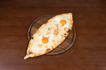 Turkish pide with mozzarella cheese and egg on a table in a restaurant on a wooden stand
