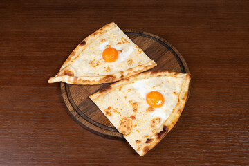 Turkish pide with mozzarella cheese and egg on a table in a restaurant on a wooden stand