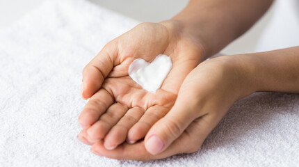 Love your body. Female hands with cream in heart shape, closeup
