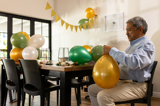 Arranging man positioning metallic gold and green balloons in home dining room, copy space