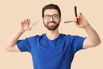Bearded young man with straight razor and scissors on beige background