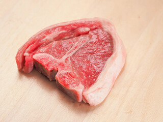 One fresh lamb loin chop on a wooden board. Expensive high quality meat product with bone for frying.