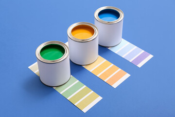 Cans of different paint and color palettes on blue background