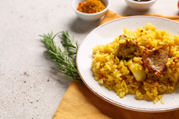 Plate of tasty pilaf with rosemary and bowl of spices on white background, closeup