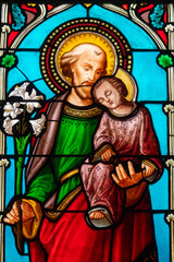 Fototapeta premium Stained glass (19th century) of Saint Joseph holding baby Jesus Christ in his arms.
