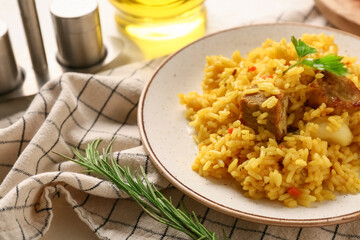 Plate with tasty pilaf and rosemary on table, closeup