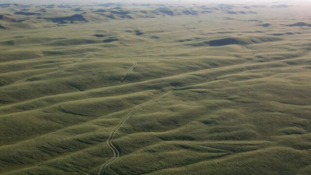 Vast mongolian steppe panorama unveiling gentle hills and winding dirt road