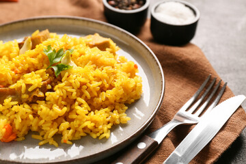 Plate with tasty pilaf and bowl of salt on black background, closeup
