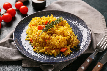 Plate of tasty pilaf with rosemary and cherry tomatoes on dark background, closeup