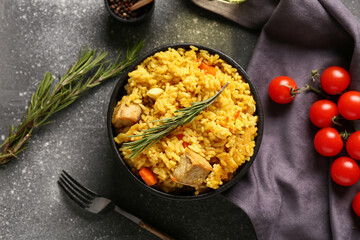 Bowl of tasty pilaf with rosemary and cherry tomatoes on grey background