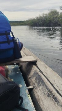 Man wearing life jacket taking water out of the traditional wooden hollowed dugout canoe bow. Person removing flood from the vessel. Side view of kayak in the Amazon forest river. Sinking boat. 