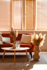 Interior of stylish living room with brown sofa, laptop, coffee table and pampas grass