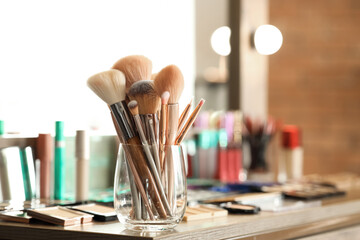 Holder with brushes on makeup artist's table in studio, closeup