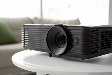 Modern projector on white table in living room, closeup