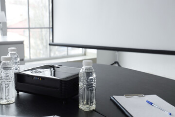 Projector with bottles of water on table in conference hall, closeup