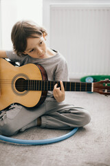 Young boy learning to play acoustic guitar at home