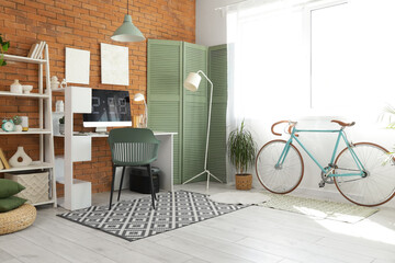 Interior of home office with workplace, shelf unit and bicycle