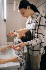 Mother helping son washing hands in bathroom sink