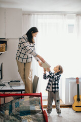 Mother giving book to son in bedroom: homeschooling during quarantine