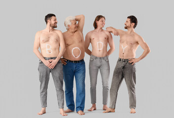 Group of men with word BODY on their skin against grey background. Body positive concept