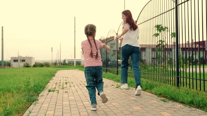Child, daughter plays with mom, run together in park. Happy family. Carefree childhood, joyful run of child mother. Little child has fun outdoors with parent. Happy kid, mom running. Family weekend