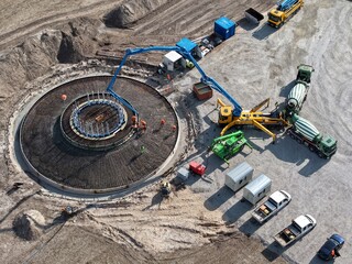 Luftbild der Erstellung des Fundaments einer Windkraftanlage mit Betonmischern und Betonpumpen,...