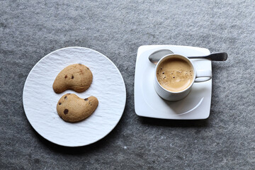White ceramic coffee cup with hot morning coffee and biscuits on a rustic wooden table. A cozy breakfast scene filled with warmth, aroma, and the charm of a simple daily ritual.