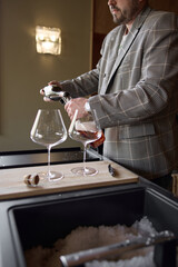 Champagne tasting, The sommelier pours sparkling wine from the decanter into a beautiful glass, Wine glasses are on the table, stylish table setting, sparkling wine bubbles