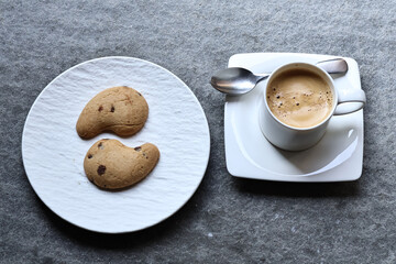 White ceramic coffee cup with hot morning coffee and biscuits on a rustic wooden table. A cozy breakfast scene filled with warmth, aroma, and the charm of a simple daily ritual.