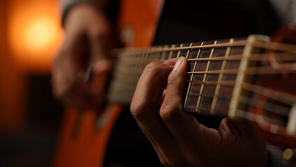 Fototapeta premium Close up view of a person playing an acoustic guitar in dim lighting