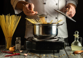A chef skillfully prepares delicious pasta by straining and adding ingredients to a pot on a...
