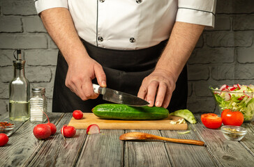 A skilled chef focuses on slicing a cucumber with precision on a wooden cutting board. Fresh vegetables surround him, creating a vibrant kitchen atmosphere filled with natural light