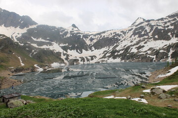 The Lakes Gemelli, covered in ice and surrounded by mountains with scattered snow, were under a cloudy sky and shrouded in a bit of fog, adding a touch of magic and mystery to the landscape.