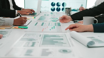 A diverse group of professionals collaborates in a modern office, analyzing financial data and charts displayed on desks and screens. Perfect for business themes. SACTR - Powered by Adobe