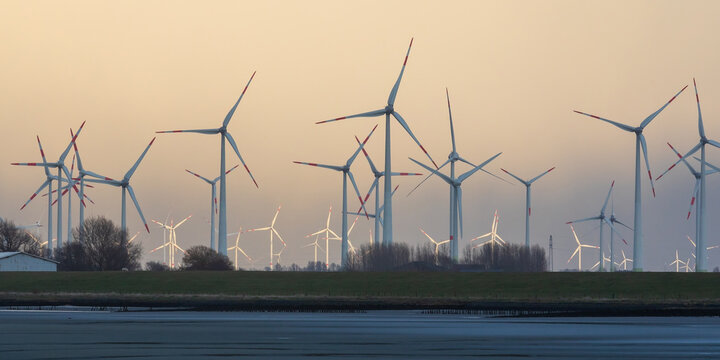 Windr&auml;der bei Wesselburenerkoog an der Eiderm&uuml;ndung an der Nordsee in Dithmarschen, Schleswig-Holstein. Windr&auml;der vorne im Schatten, hintere im Abendlicht