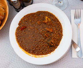 Delicious lentil soup with meat and vegetables served to table