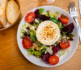 Appetizing salad of fresh vegetables served with goat cheese on plate