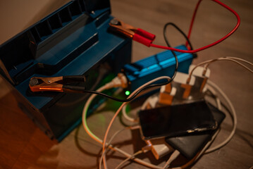 Devices charging from battery inverter in dark room. Multiple phones and powerbanks charging from...