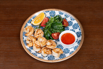 Grilled shrimp with spinach tomatoes rucolla and lemon on a plate