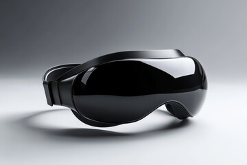 A sleek black virtual reality headset sits on a white surface with a grey background
