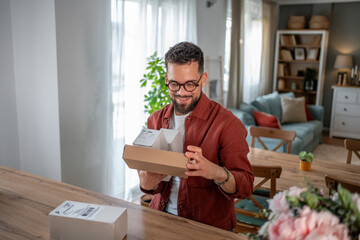 Happy man unboxing packages at home in living room