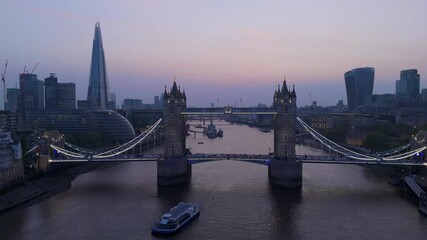 A breathtaking aerial perspective of the iconic Tower Bridge illuminated at twilight, perfectly highlighting the striking and beautiful London skyline that stretches along the River Thames