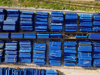 Stack of cast iron pipes in loading area waiting for transportation, drone aerial view