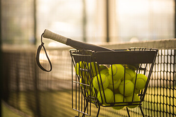 Folding basket with balls for padel classes on the court. Trainer equipment. Background with copy...