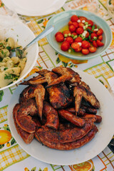 Grilled meats and vibrant sides served on a sunny outdoor table during a festive gathering