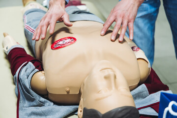 First aid training course with dummy, CPR emergency reanimation procedure on mannequin, instructor demonstrating medical training with doll, chest compression and applying bandage and tourniquet
