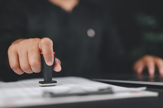 Businessman validates and manages business documents and agreements, approval stamp, signing a business contract approval of contract documents confirmation or warranty certificate,