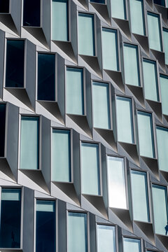 Grid of extruded windows in Copenhagen, a modern building facade, capturing urban geometry, modularity and reflective design for commercial real estate and housing in Copenhagen, Copenhagen.